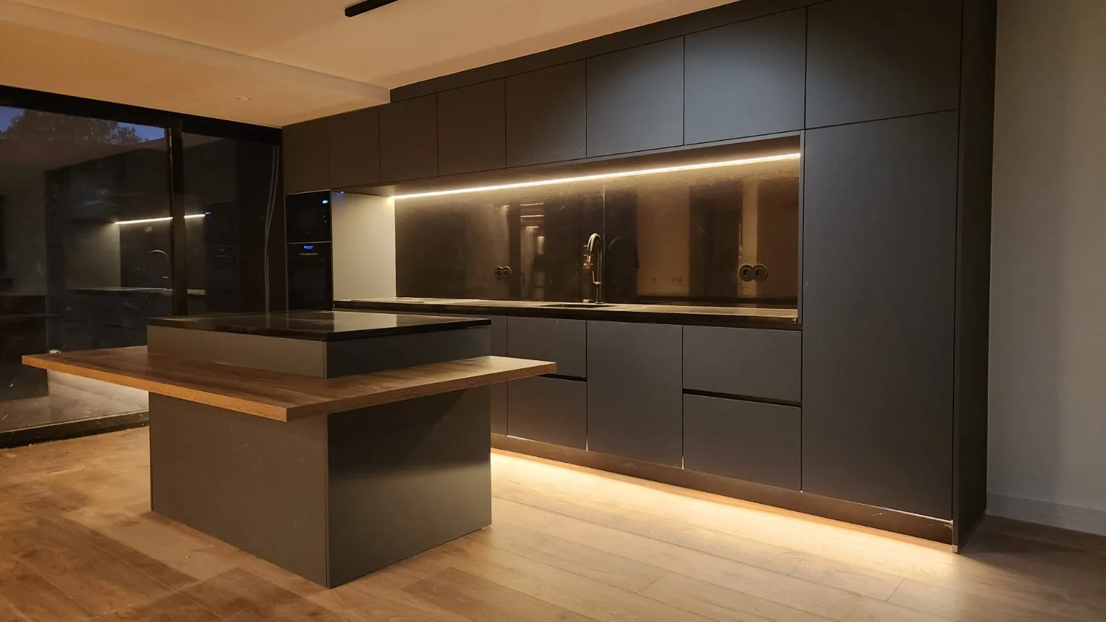 Cozinha escura com ilha em madeira e iluminação LED